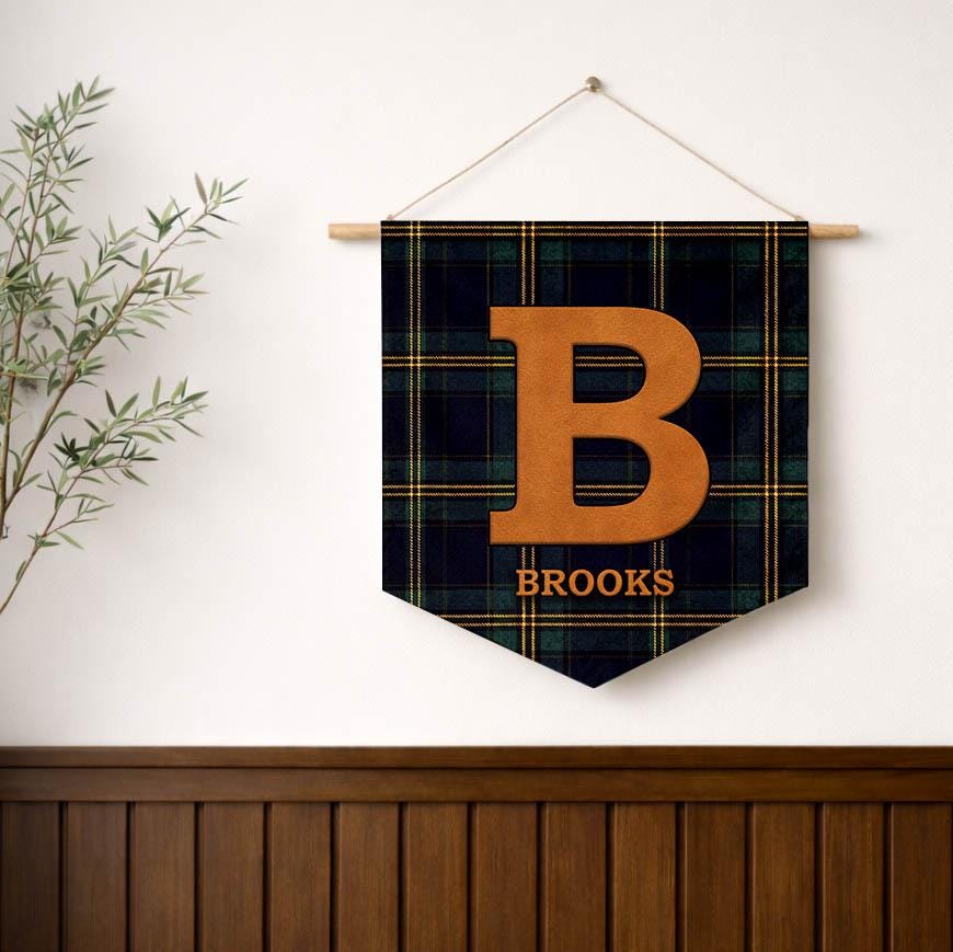 Tartan monogram name pennant reading Brooks on a white wall above wood paneling