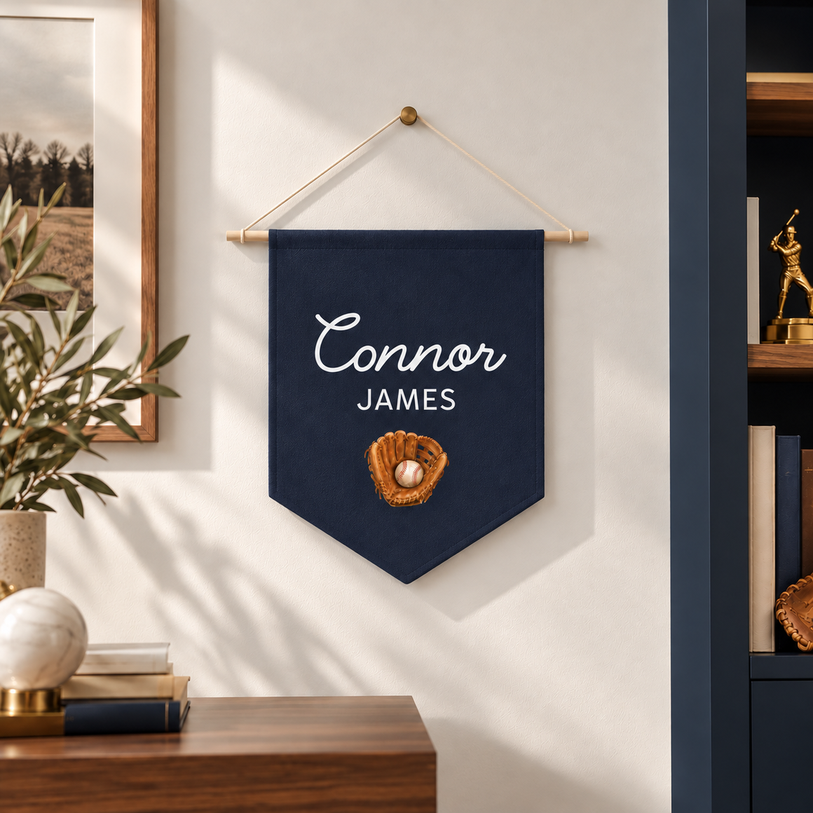 Personalized baseball glove name pennant in navy with Connor James in white script hanging in a nursery